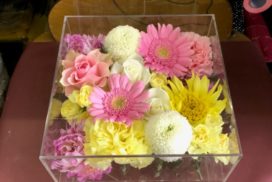 アクリルケースに収められている、ピンクのガーベラやバラなどの花々。