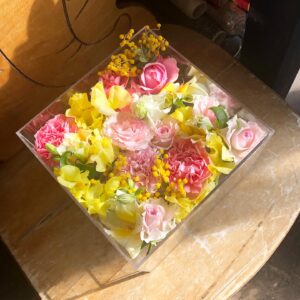 アクリルケースに収められたピンクと黄色のお別れ用の花々。