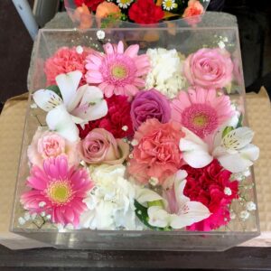 アクリルケースに収められた白とピンクと赤色のお別れ用の花々。