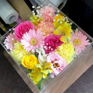 アクリルケースに収められたピンクと黄色のお別れ用の花々。