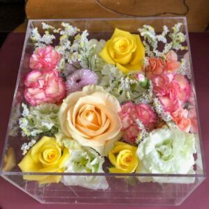 アクリルケースに収められた黄色と白とピンクのお別れ用の花々。